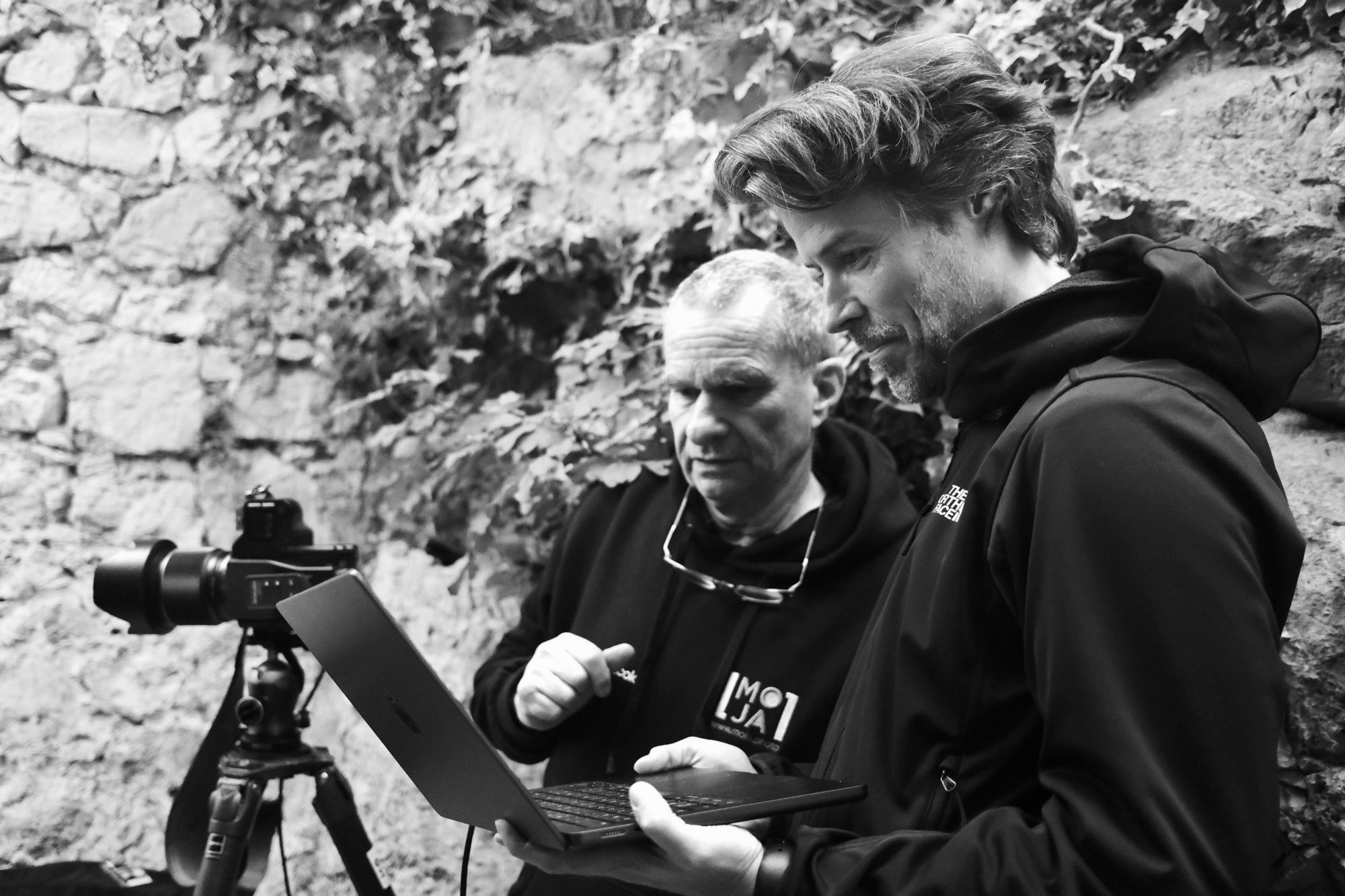 Jan Wischermann checking images on a laptop on set, next to a camera on a tripod